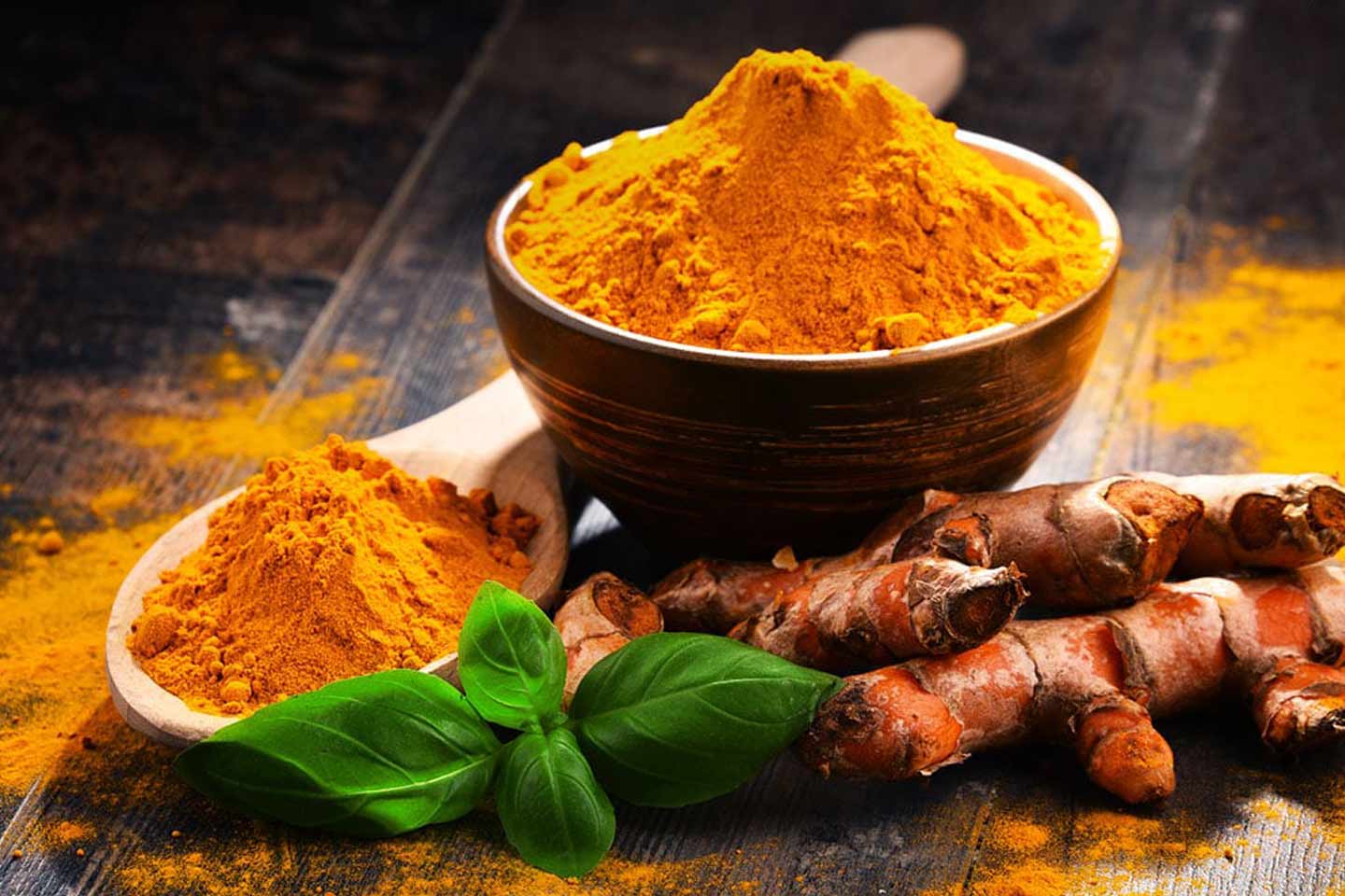 Turmeric plant and powder in a bowl