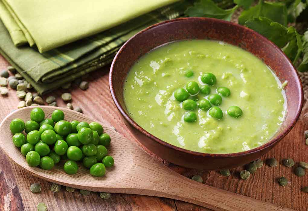 homemade pea soup in a brown bowl. Fresh peas on a wooden spoon. pea soup