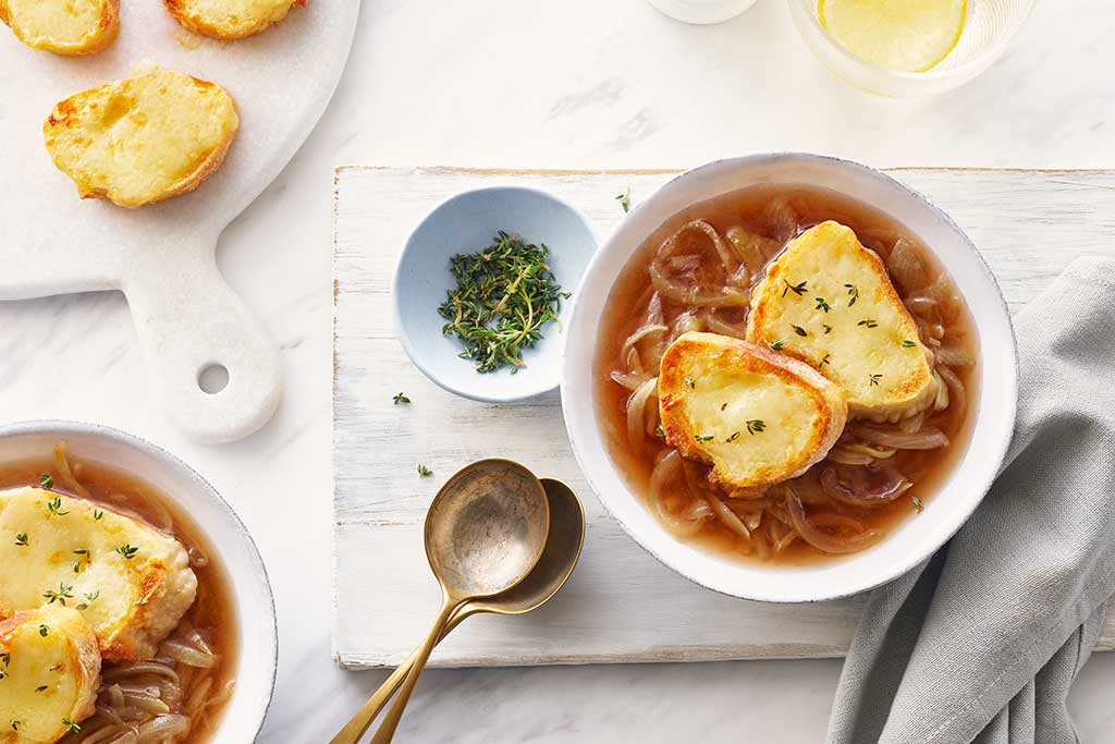 onion soup in a white bowl on a table with bread