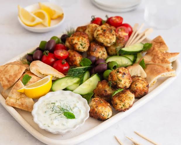 Minty chicken meatballs on a platter. With salad and yoghurt sauce