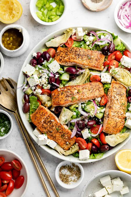 Easy Lemon and herb salmon recipe served with Greek salad, fresh olives and feta cheese 